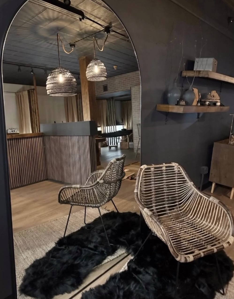 Boutique lounge with arched mirror, rattan chairs, and warm ambient lighting
