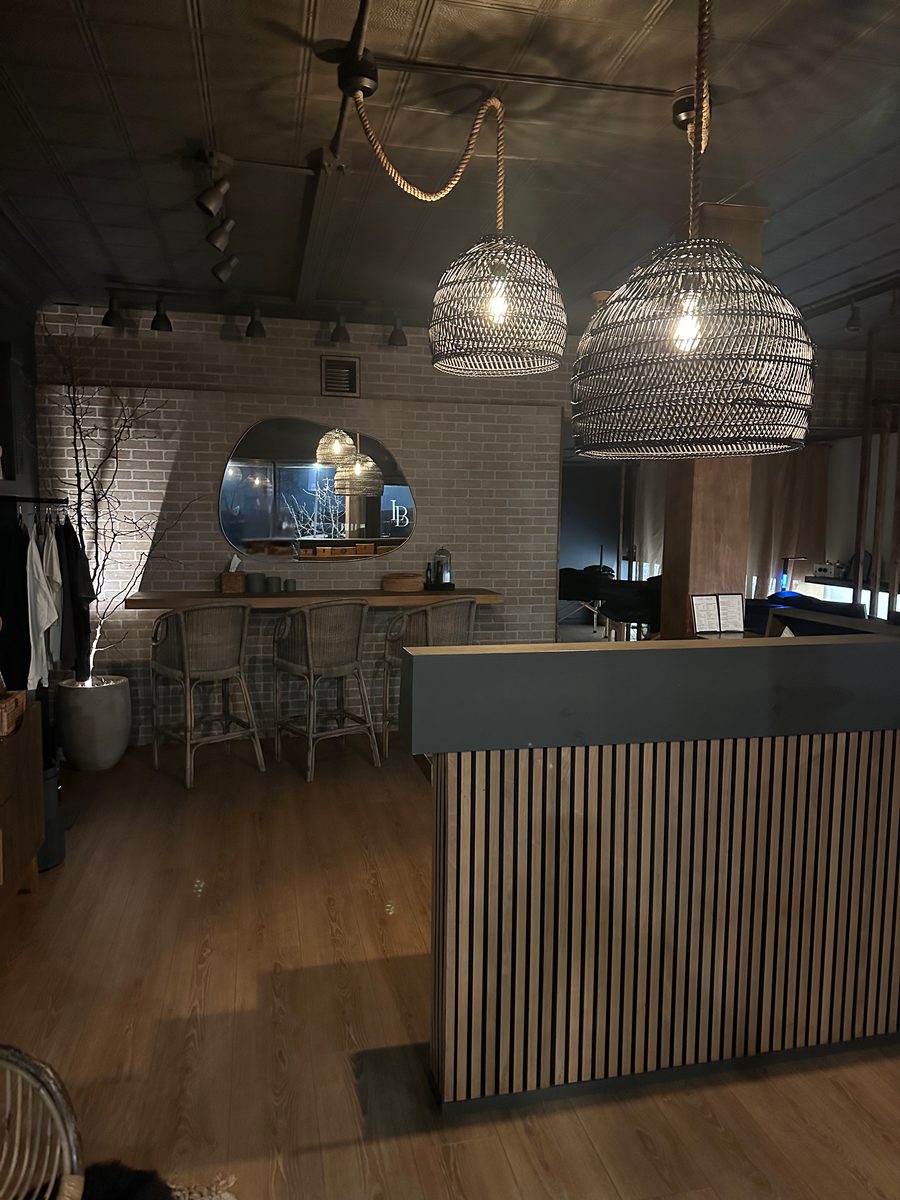 Lash & Brow Boutique reception with rattan pendants, brick walls, and warm wood detail